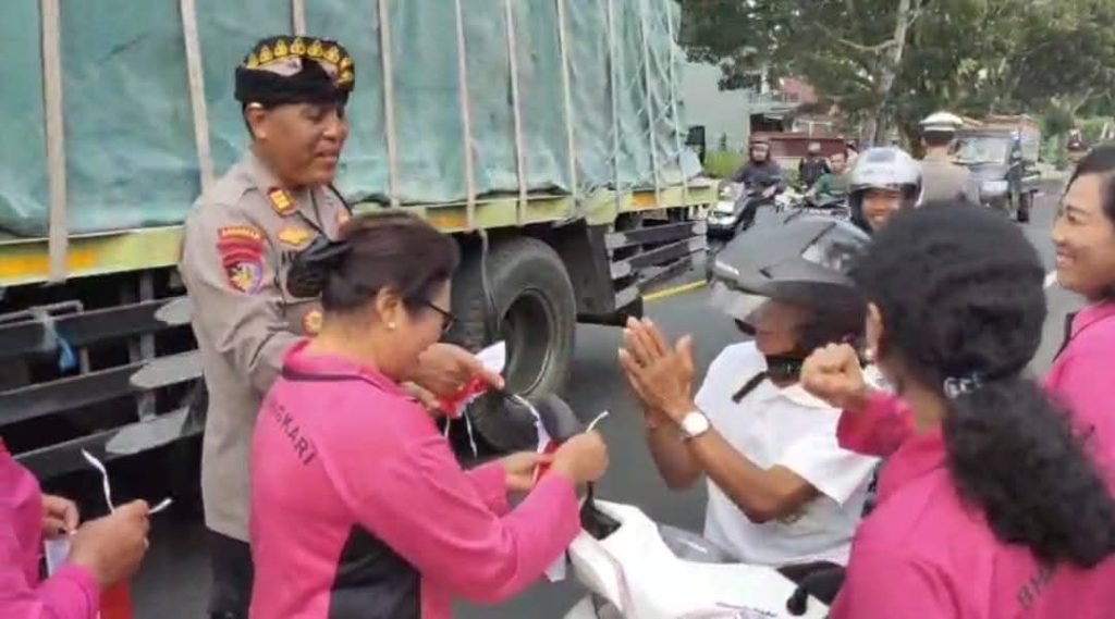 Kapolsek Selemadeg Timur AKP I Nyoman Artadana bersama Ketua Bhayangkari Ranting Seltim membagikan bendera Merah Putih kepada pengendara di depan Mako Polsek Seltim dalam rangka menyambut HUT ke-80 RI. (Foto: Istimewa)
