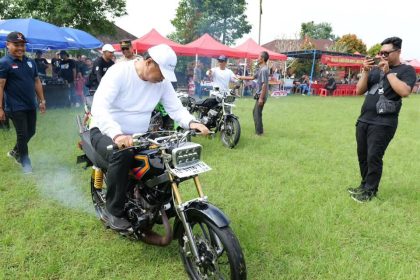 Wakil Bupati Tabanan, I Made Dirga, menjajal salah satu motor dua tak modifikasi saat membuka Event 1/2 Kopling Passion Engine Two Stroke Racing Blayer Competition 2025 di Lapangan Bima Sakti, Desa Penatahan, Kecamatan Penebel, Tabanan, Minggu (10/08/2025). (Foto: Istimewa)