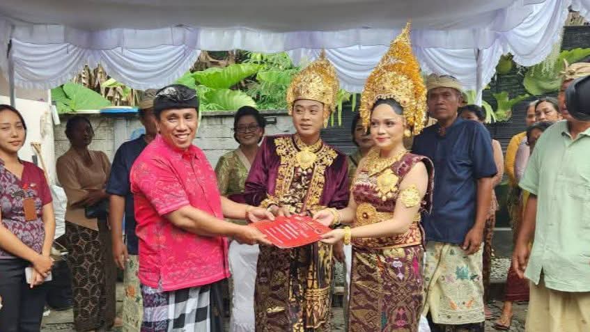 Perbekel Desa Gadungan, I Wayan Muliartana, menyerahkan akta perkawinan kepada pasangan pengantin dalam program Semara Ratih di Desa Gadungan, Kecamatan Selemadeg Timur, Tabanan, Senin (25/8/2025). (Foto: Istimewa)