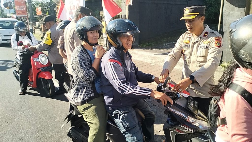 Kapolsek Selemadeg, Kompol I Wayan Suastika, S.H., secara langsung membagikan bendera Merah Putih kepada pengendara sepeda motor dalam aksi simpatik menyambut HUT ke-80 RI di depan Mako Polsek Selemadeg, Tabanan, Kamis (7/8/2025). (Foto: Istimewa)