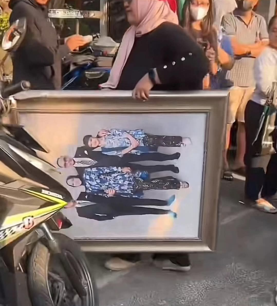 “Seorang warga terlihat membawa bingkai foto keluarga dari dalam rumah pejabat yang menjadi sasaran penjarahan saat gelombang aksi massa berlangsung.” (Foto: Istimewa)