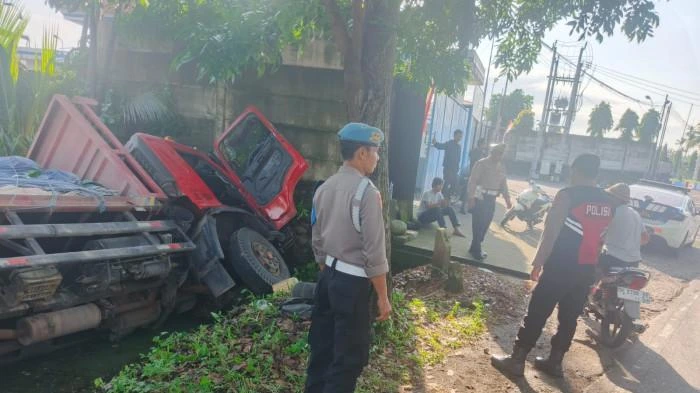 Petugas kepolisian bersama warga mengevakuasi truk bermuatan semen yang terperosok di pinggir Jalan Raya Denpasar–Gilimanuk, Desa Pangyangan, Pekutatan, Jembrana, Minggu (2/11/2025). (Foto: Istimewa)