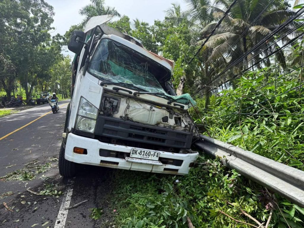 Sebuah truk tronton Isuzu bernomor polisi DK-8160-FA tampak ringsek di bagian depan setelah menabrak pohon perindang dan pembatas jalan di ruas Jalan Nasional Denpasar–Gilimanuk, wilayah Banjar Dinas Soka Kelod, Desa Antap, Kecamatan Selemadeg, Kabupaten Tabanan, Sabtu (10/1/2026). Tidak ada korban jiwa dalam peristiwa tersebut. (Foto: Istimewa)