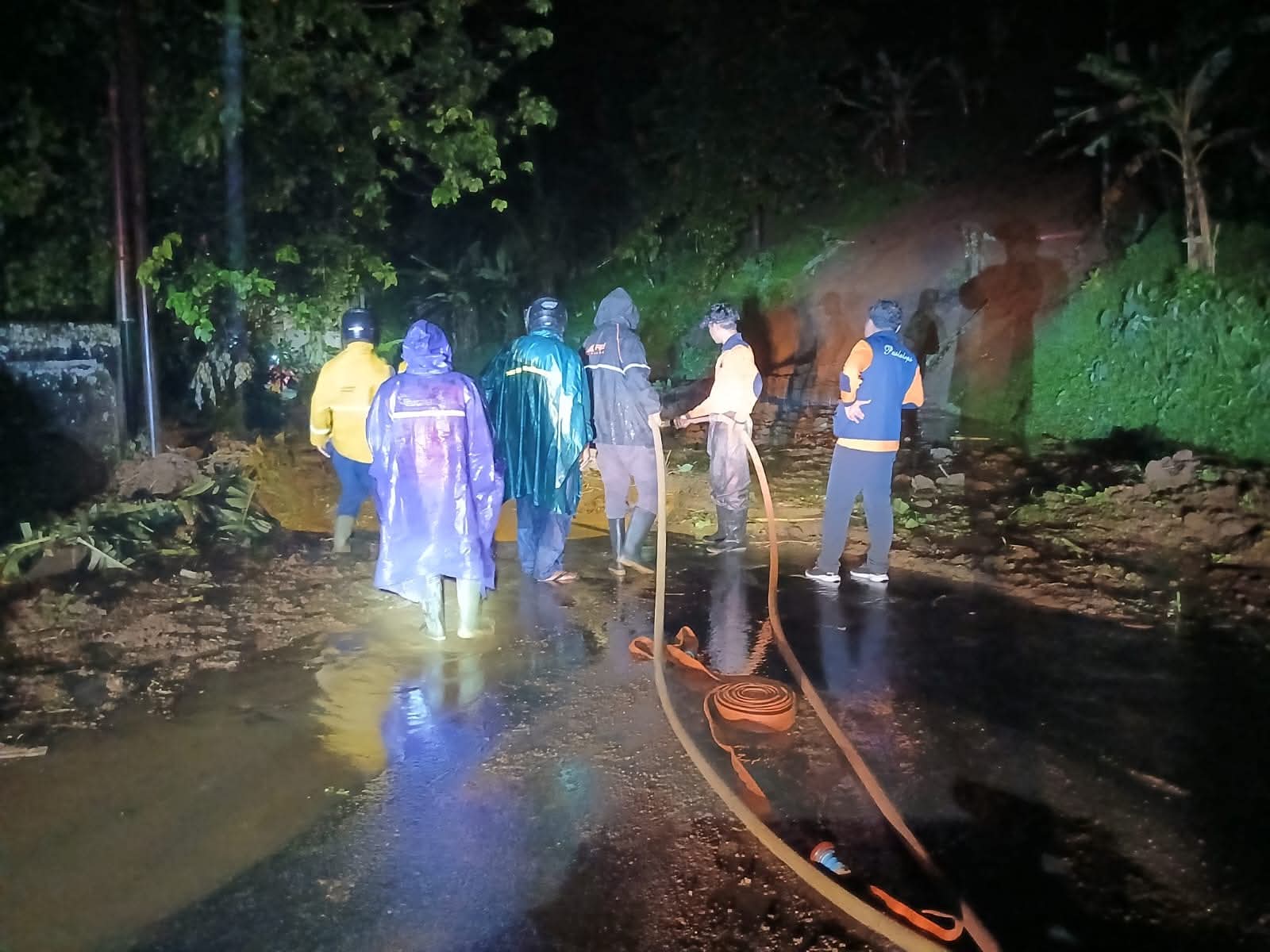 Petugas BPBD Kabupaten Tabanan bersama tim terkait melakukan penanganan dan pembersihan material longsor yang menutup badan jalan di wilayah Kecamatan Pupuan, Kamis (15/1/2026) malam, akibat hujan deras berkepanjangan yang mengguyur kawasan tersebut. (Foto: Istimewa)