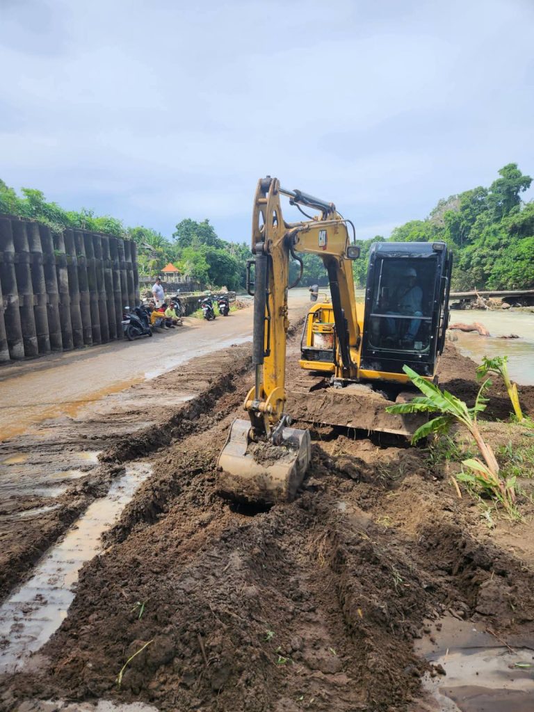 Alat berat dikerahkan Pemdes Beraban bersama dinas terkait untuk meratakan endapan lumpur dan membersihkan saluran air di jalur penghubung Beraban–Tibubiu, Kecamatan Selemadeg Timur, guna memulihkan akses jalan akibat genangan dan sedimentasi pascahujan. (Foto: Istimewa)