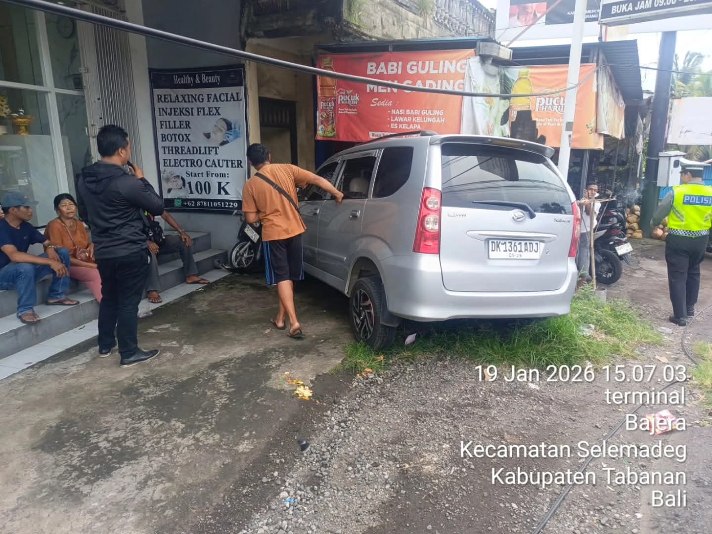 Sebuah mobil Daihatsu Xenia bernomor polisi DK 1361 ADJ terlihat berada di area depan pertokoan di Banjar Dinas Bajera, Kecamatan Selemadeg, Tabanan, usai menabrak sepeda motor yang terparkir akibat pengemudi diduga mengantuk, Senin (19/1/2026). Peristiwa tersebut langsung ditangani personel Polsek Selemadeg untuk pengamanan lokasi kejadian. (Foto: Istimewa)