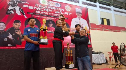 Penyerahan piala kepada perwakilan SMKN 2 Tabanan usai dinobatkan sebagai Juara Umum I tingkat SMA pada Kejuaraan Silat Bupati Tabanan Cup 2026 di GOR Debes, Minggu (12/4). (Foto: Istimewa)
